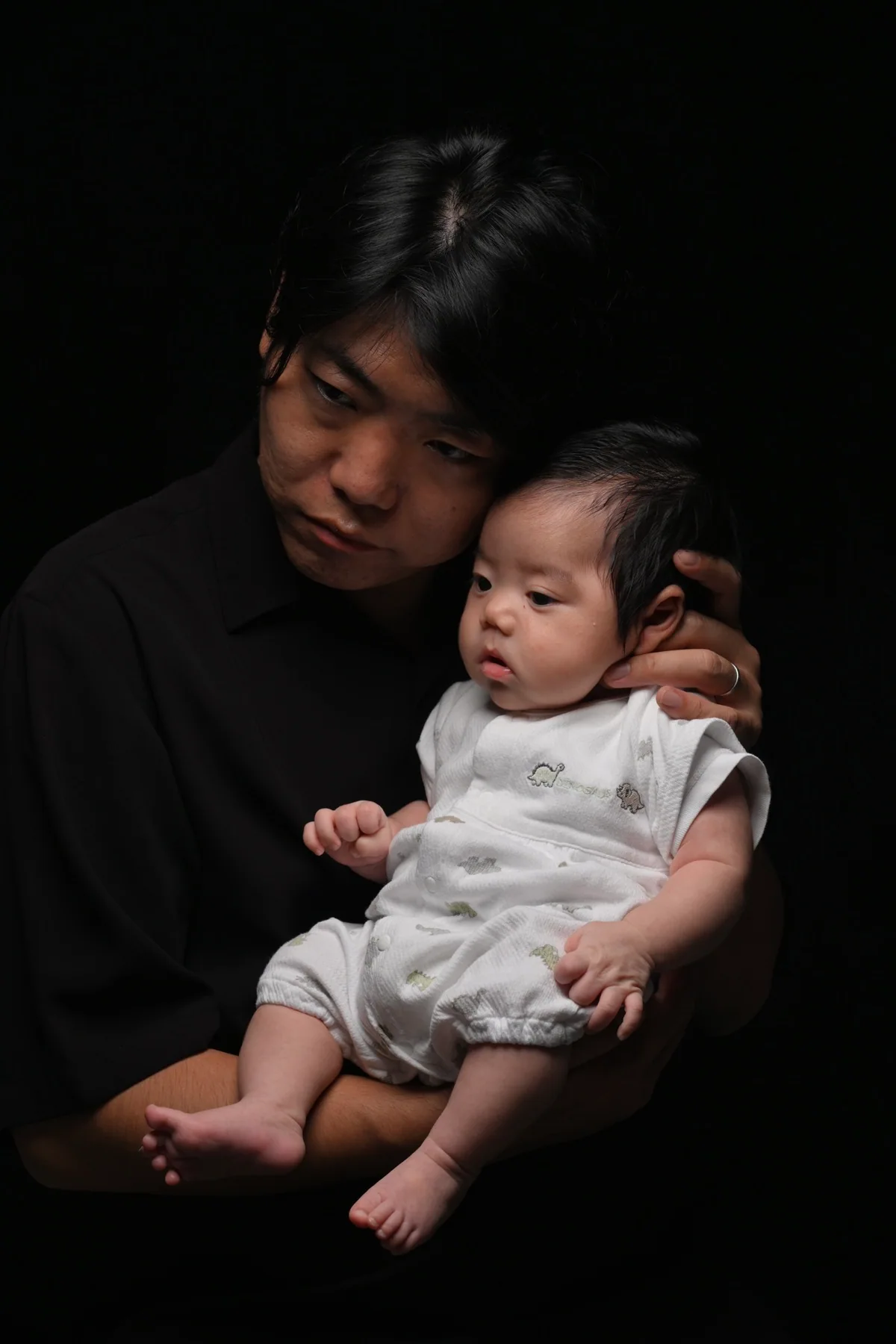 父親が赤ちゃんの頭に手を添えるLIGHT & SHADOWの親子写真