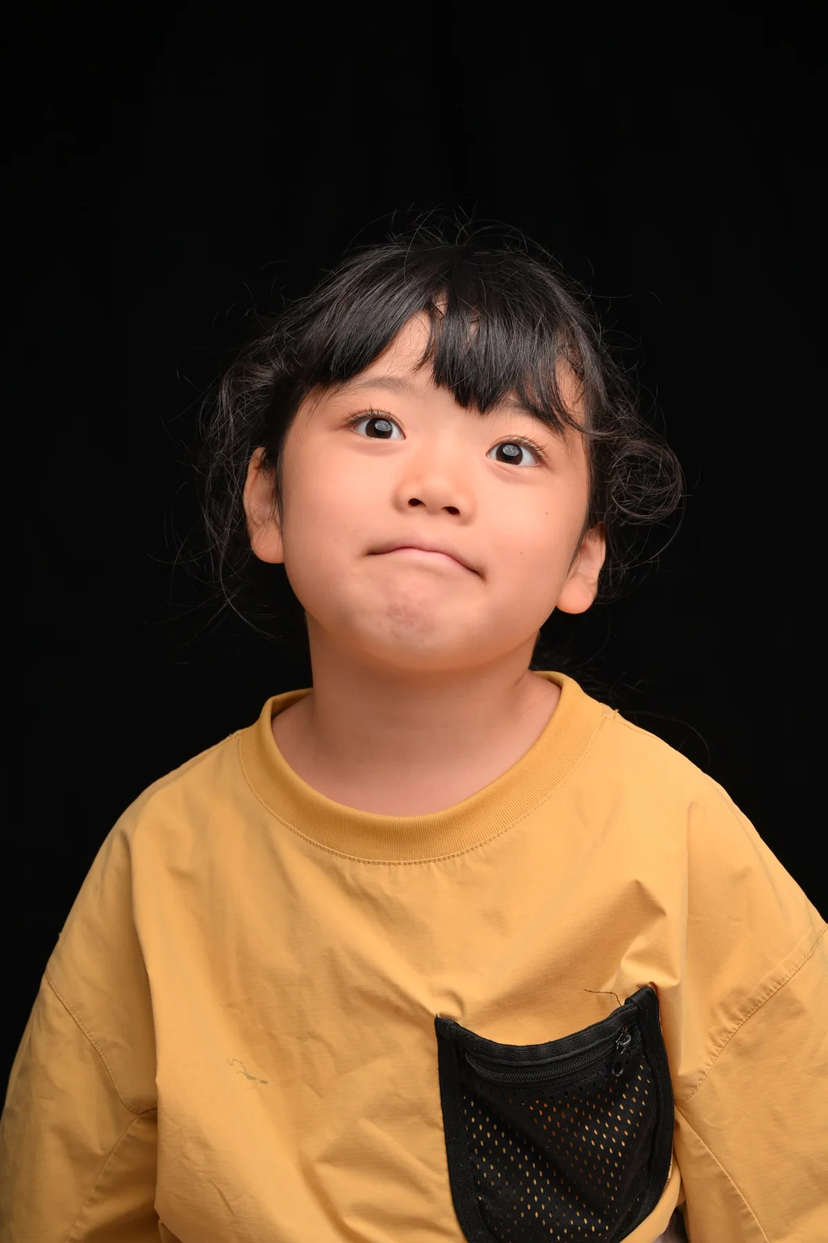 黒背景で自然な表情を見せる子どものポートレート